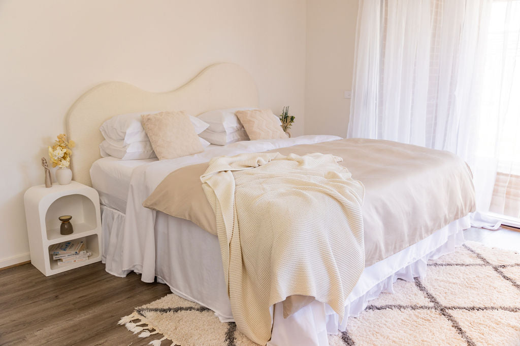 aesthetically styled bed with white sheets and beige quilt covers, styled with coverlet, throw and decorative pillows