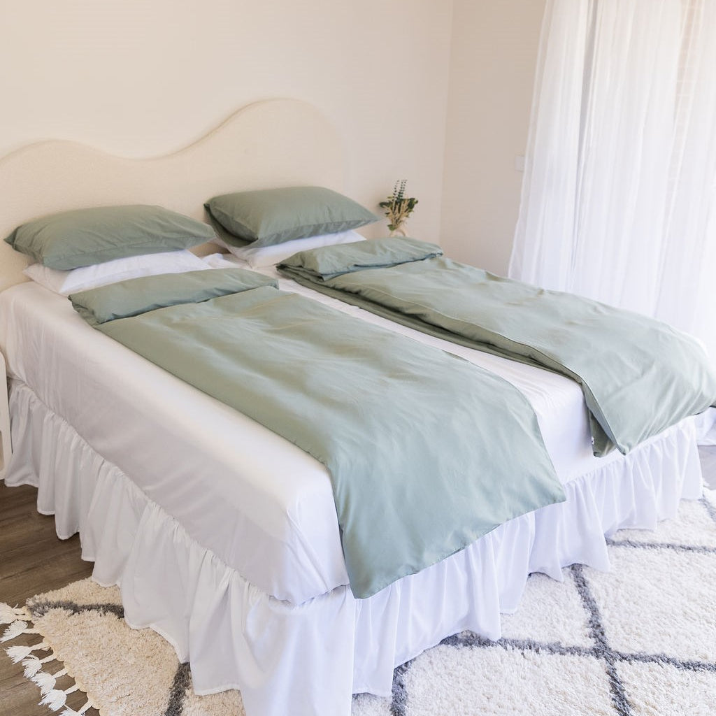 Bed styled traditional Scandinavian way 2x single doonas folded in half with white sheet and eucalyptus green quilt covers