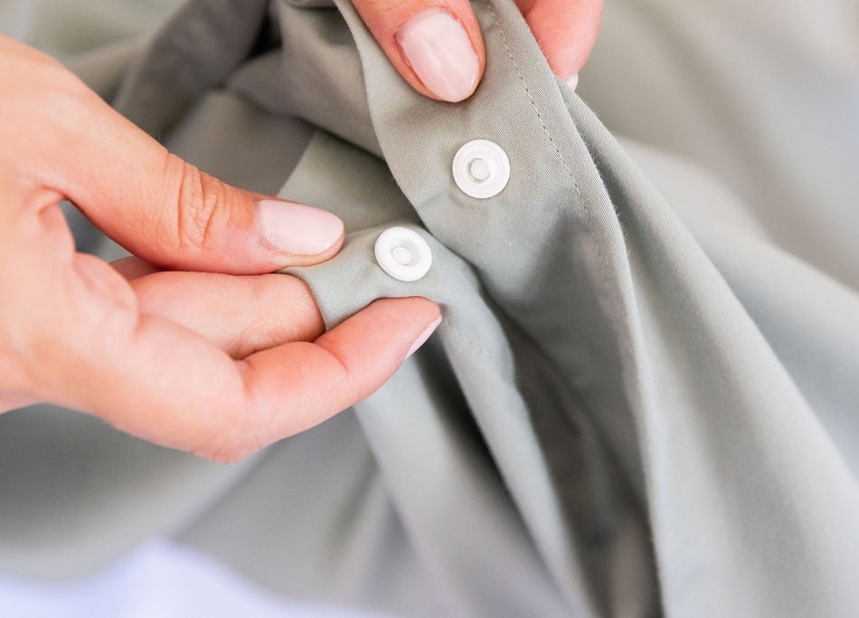 female hands clipping together eucalyptus green quilt cover snap clips