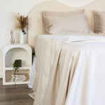 Close up of King/Queen bamboo cotton sheet set in beige styled on bed with nice sidetable