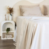 Close up of King/Queen bamboo cotton sheet set in beige styled on bed with nice sidetable