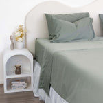 Close up of King/Queen bamboo cotton sheet set in eucalyptus green styled on bed with nice side table