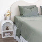 Close up of King/Queen bamboo cotton sheet set in eucalyptus green styled on bed with nice side table