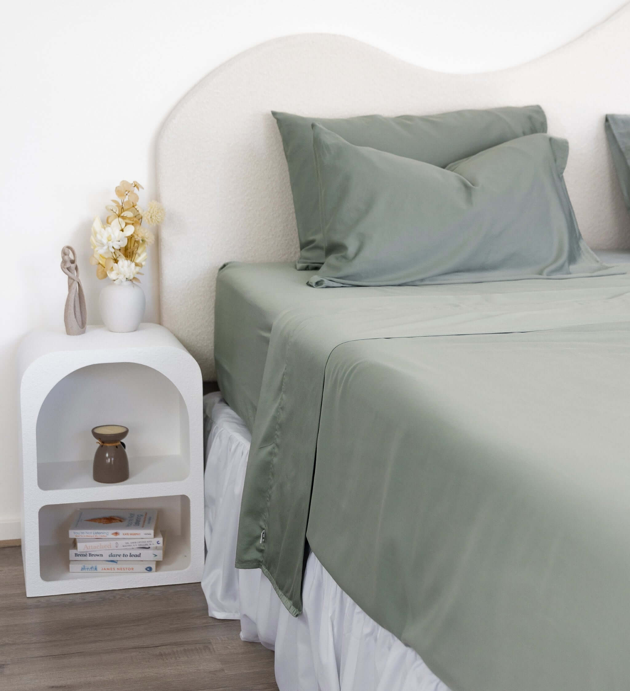 Close up of King/Queen bamboo cotton sheet set in eucalyptus green styled on bed with nice side table