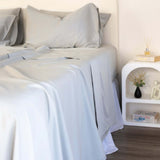 Close up of King/Queen bamboo cotton sheet set in grey sage styled on bed with nice side table