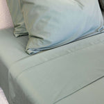 Close-up of bamboo cotton sateen weave in eucalyptus green, hemming visual