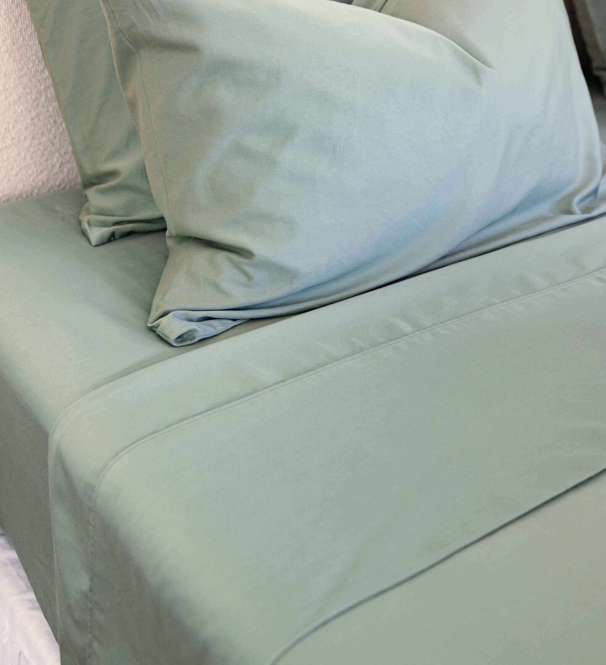Close-up of bamboo cotton sateen weave in eucalyptus green, hemming visual
