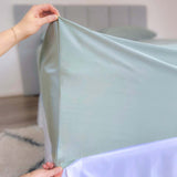hands holding corner of eucalyptus green fitted sheet showing 46cm pocket depth 