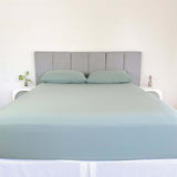 bed styles with eucalyptus green fitted sheet and 2 matching pillows with grey headboard