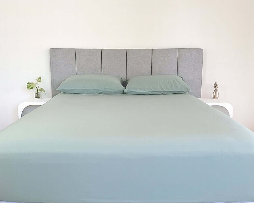 bed styles with eucalyptus green fitted sheet and 2 matching pillows with grey headboard