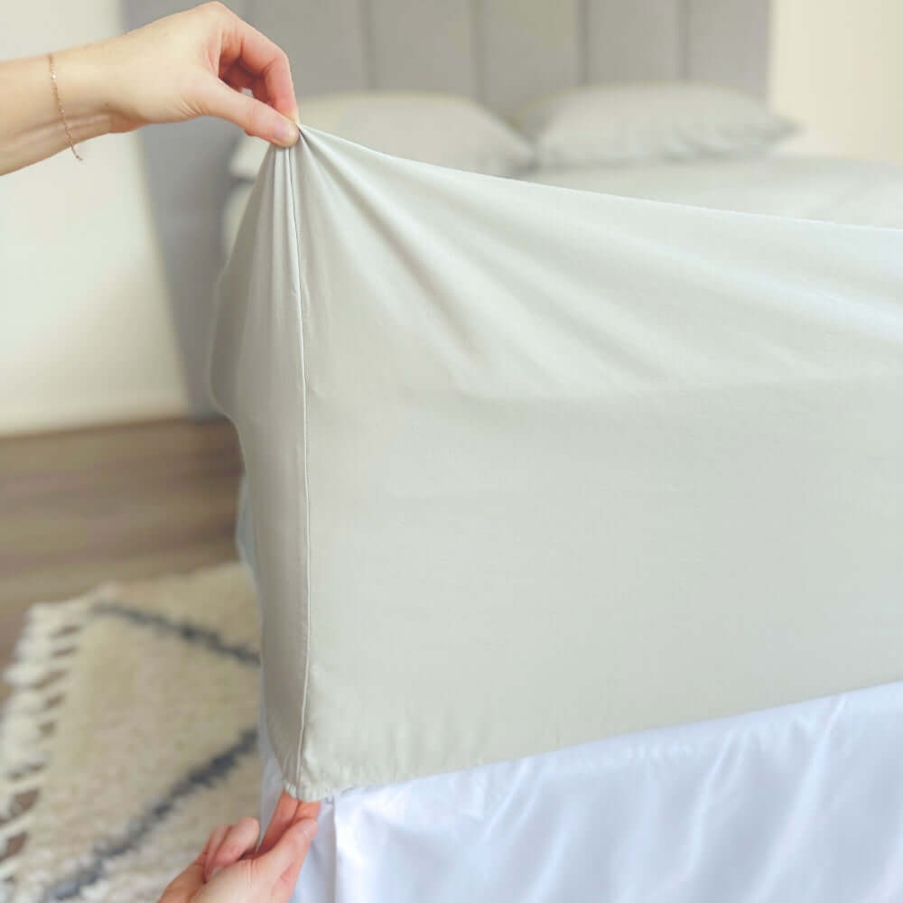 hands holding corner of grey sage fitted sheet showing 46cm pocket depth 