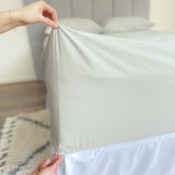 hands holding corner of grey sage fitted sheet showing 46cm pocket depth 