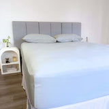 corner view of bed styles with grey sage fitted sheet and 2 matching pillows with grey headboard