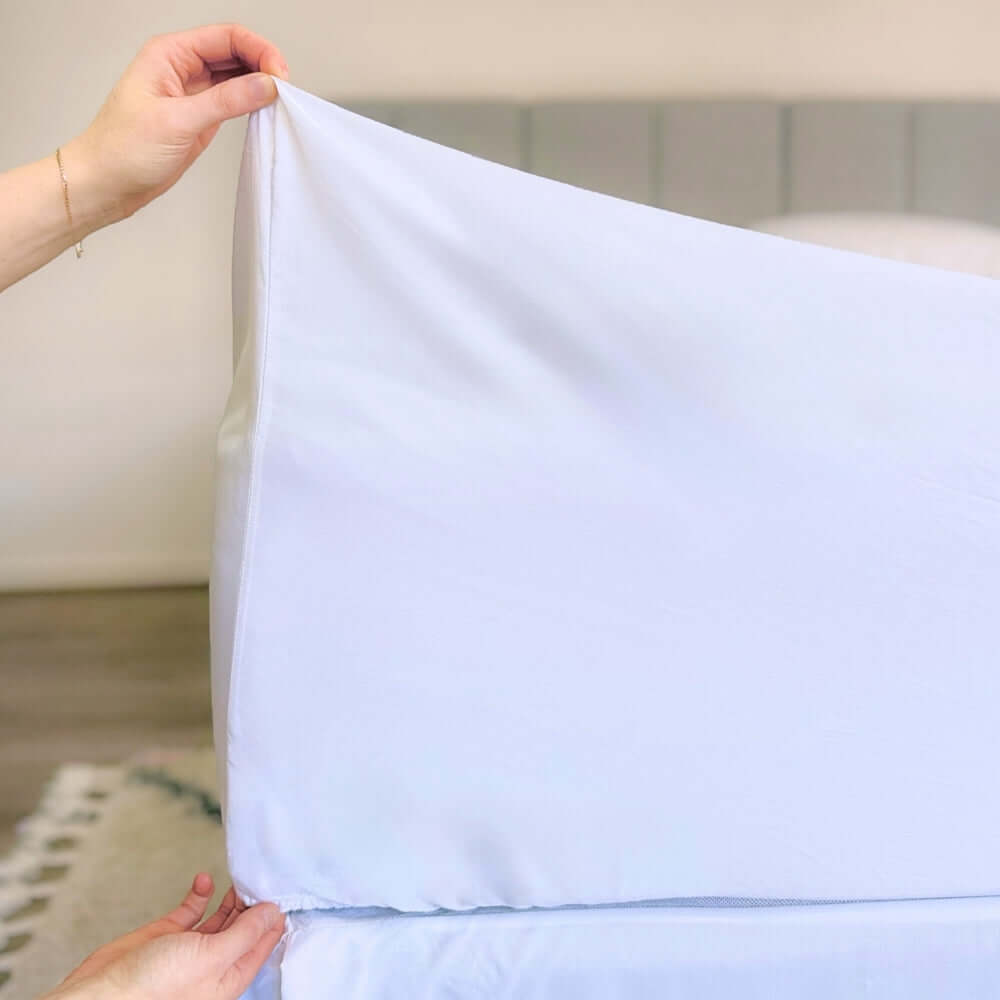hands holding corner of white fitted sheet showing 46cm pocket depth 