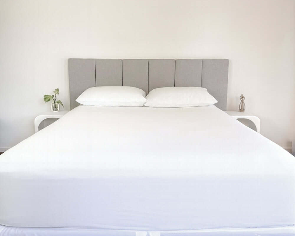 bed styles with white fitted sheet and 2 matching pillows with grey headboard