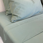 Close-up of bamboo cotton sateen weave in eucalyptus green, hemming visual
